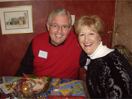 A man and woman sitting at a table with christmas presents.